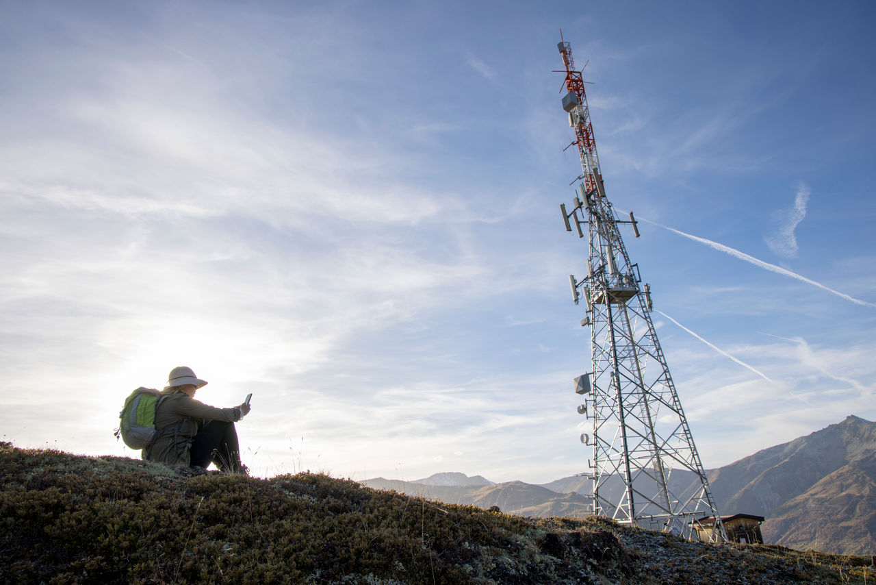 Person checking their phone near a cell tower.