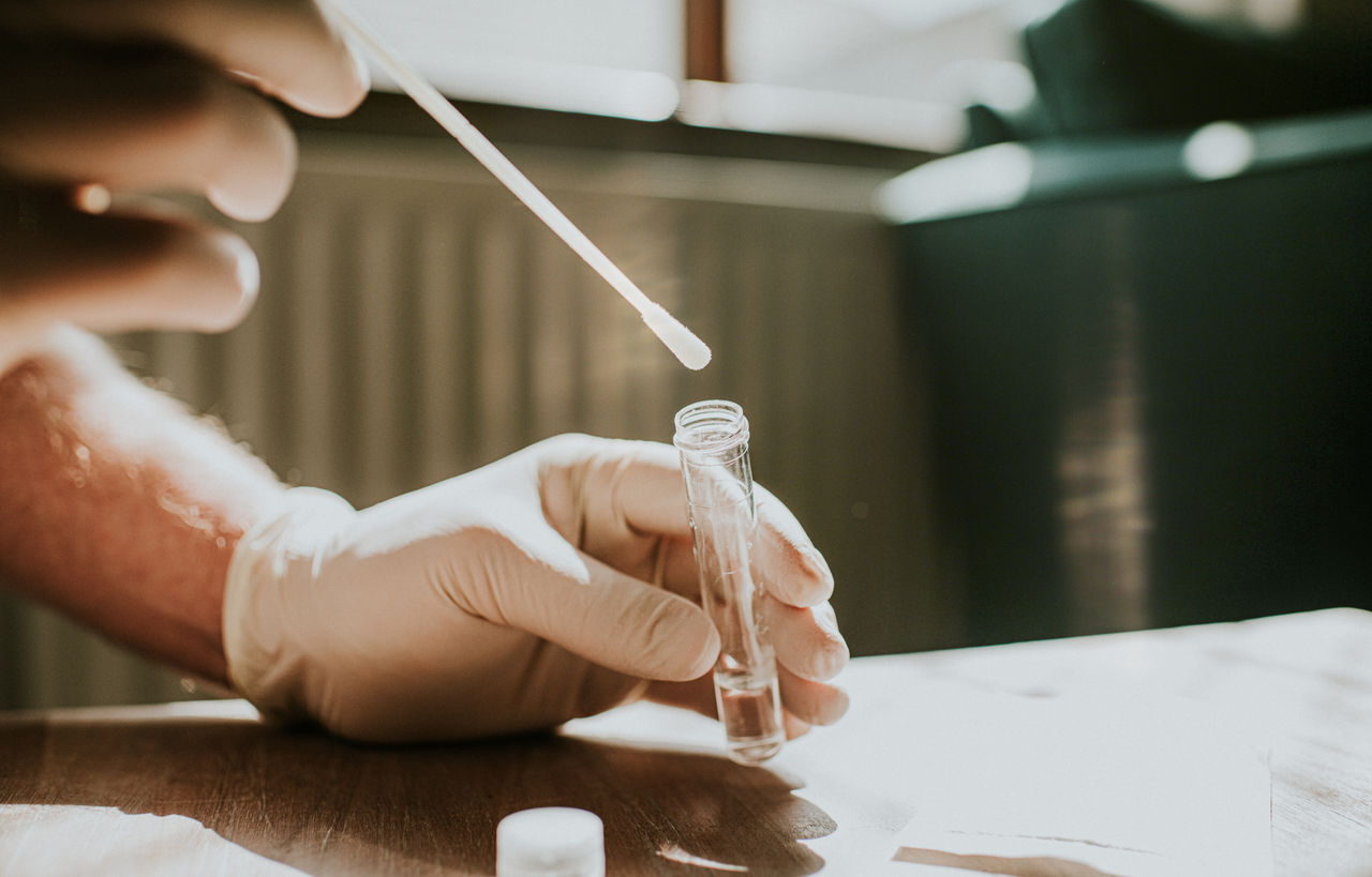 Technician putting a swab into a test tube.