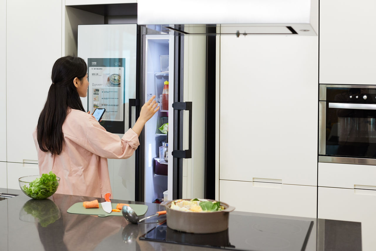 Woman opens a connected refrigerator door 