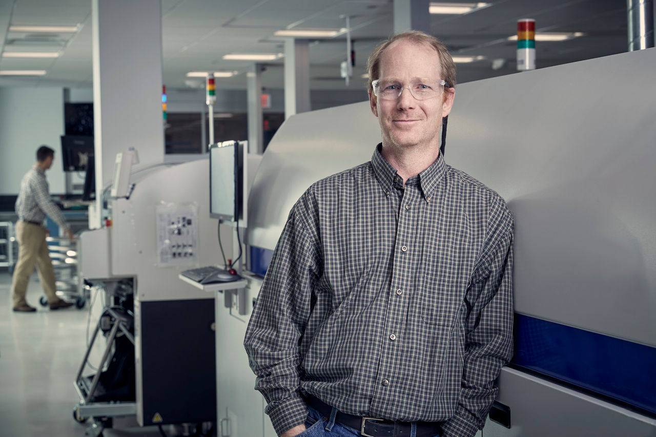 An engineer inspects an electronic component under a microscope in a modern laboratory environment.