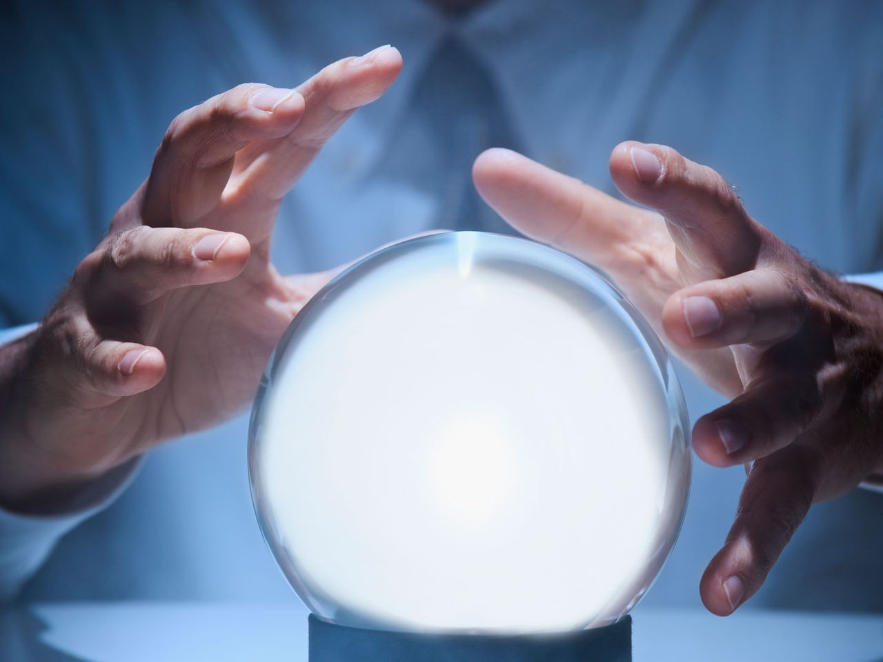 Two hands hovering around a crystal ball.  