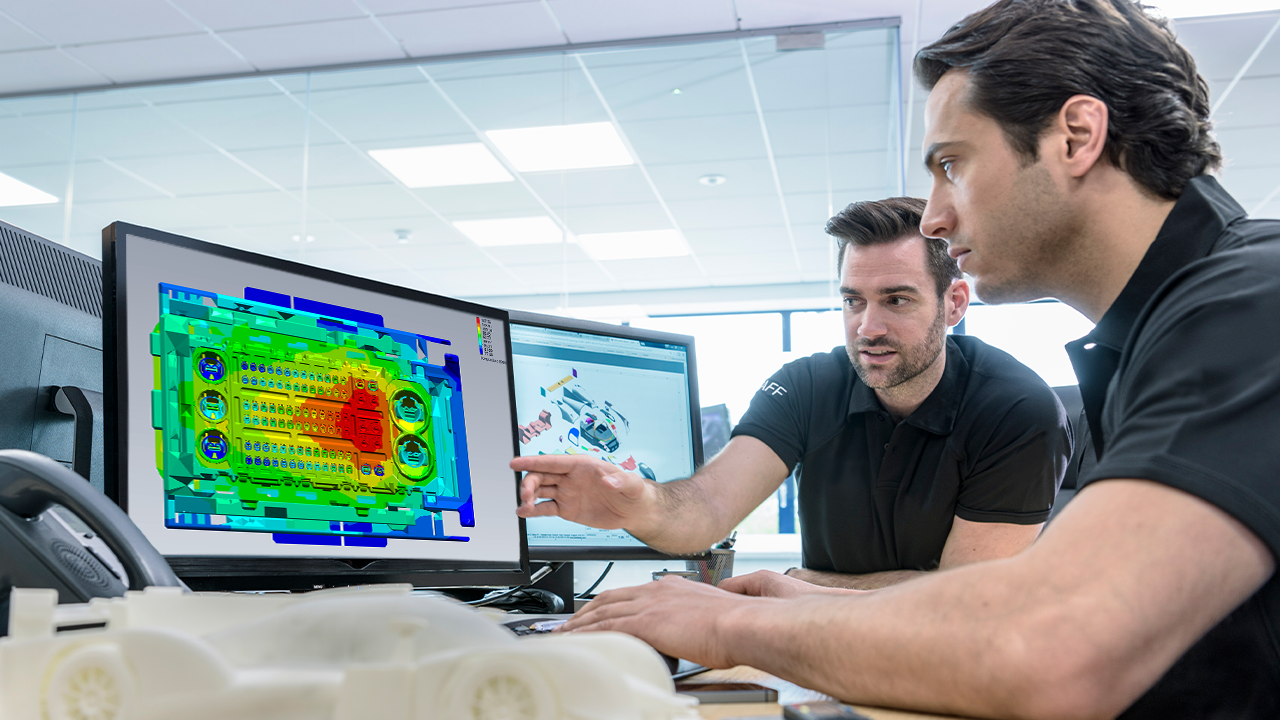 Engineers discuss a heat map of high-performance automotive components under testing.