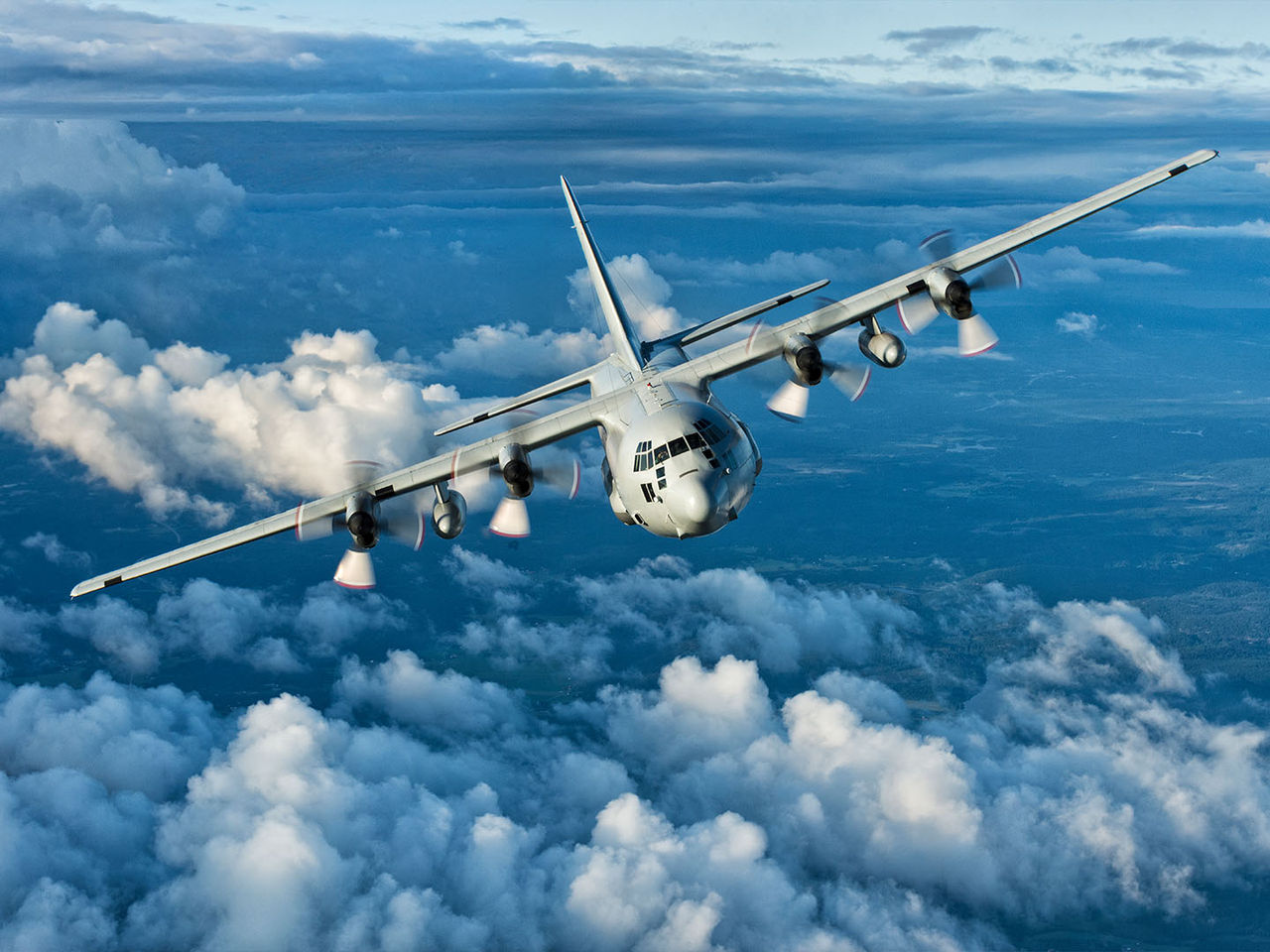 A military plane in flight above the clouds.