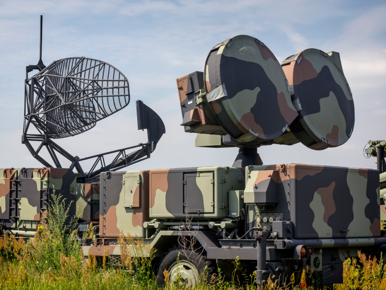 A fleet of military vehicles equipped with RF antennas.