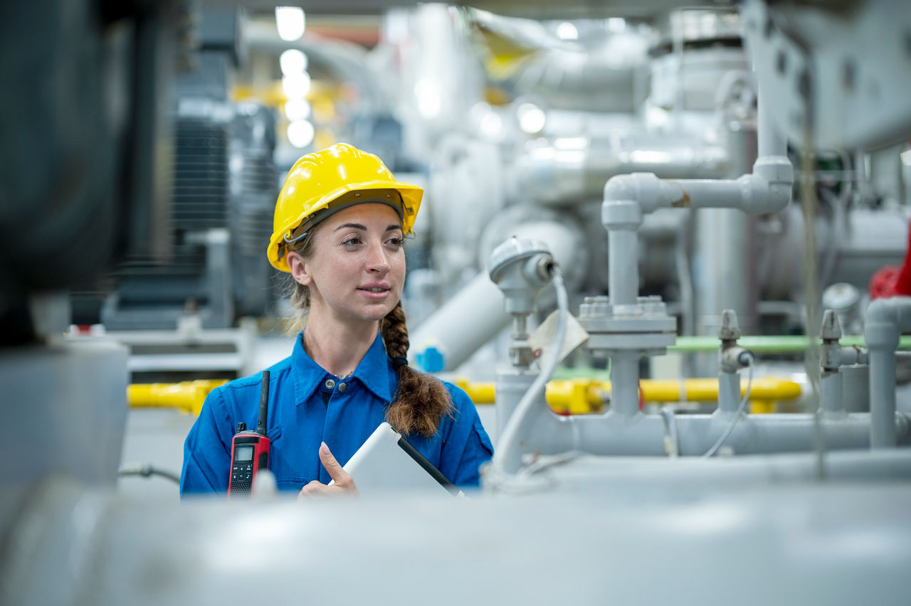 Engineer in a factory with industrial equipment.