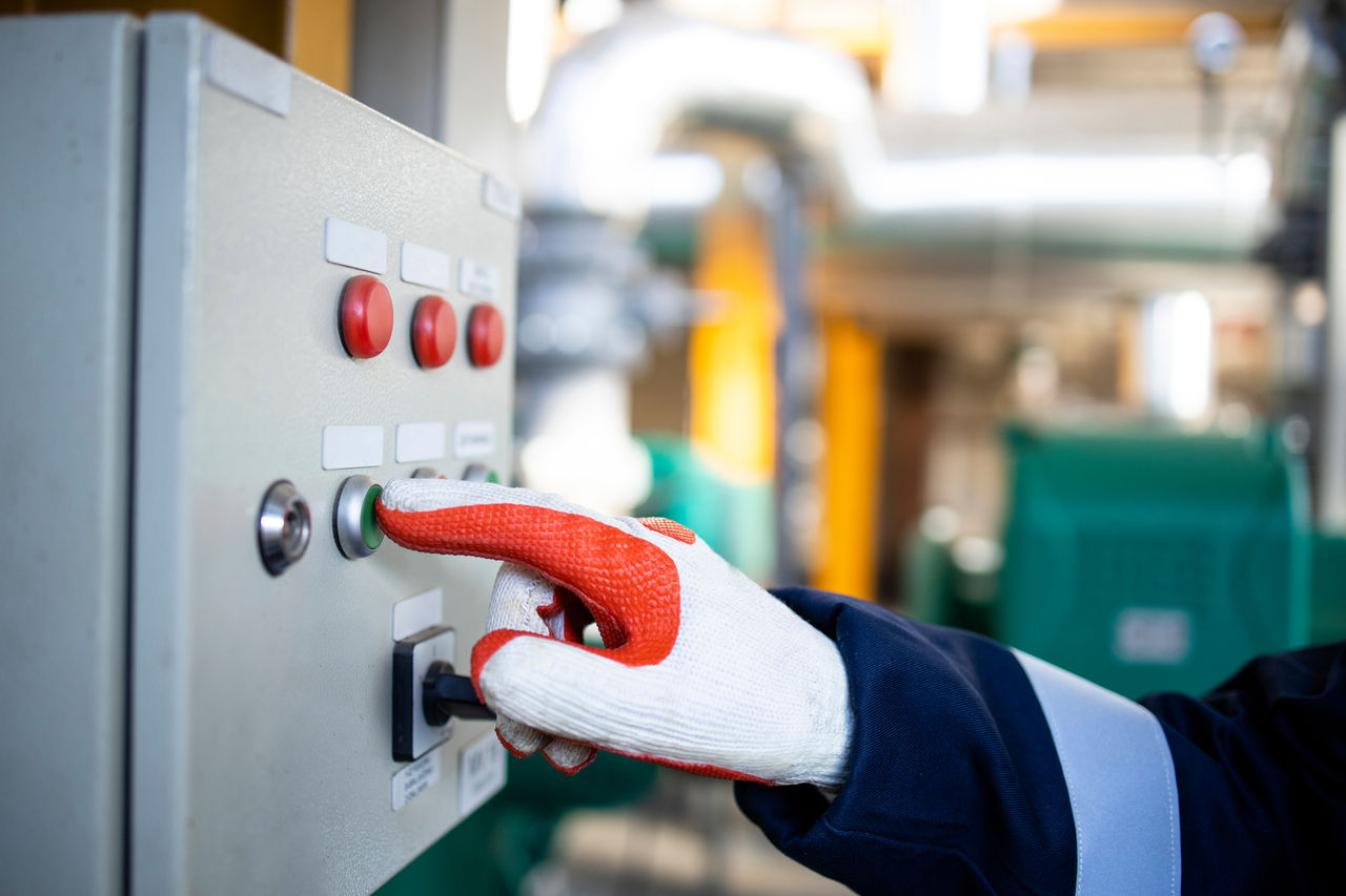 Close up view of an unrecognizable worker turning power on in oil and gas refinery.
