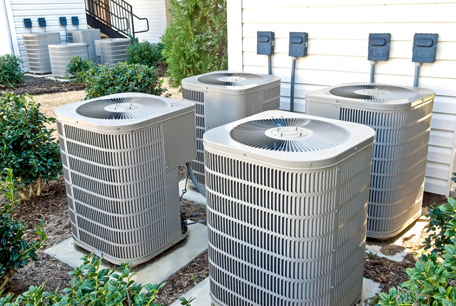 Outdoor residential HVAC units near a building. 