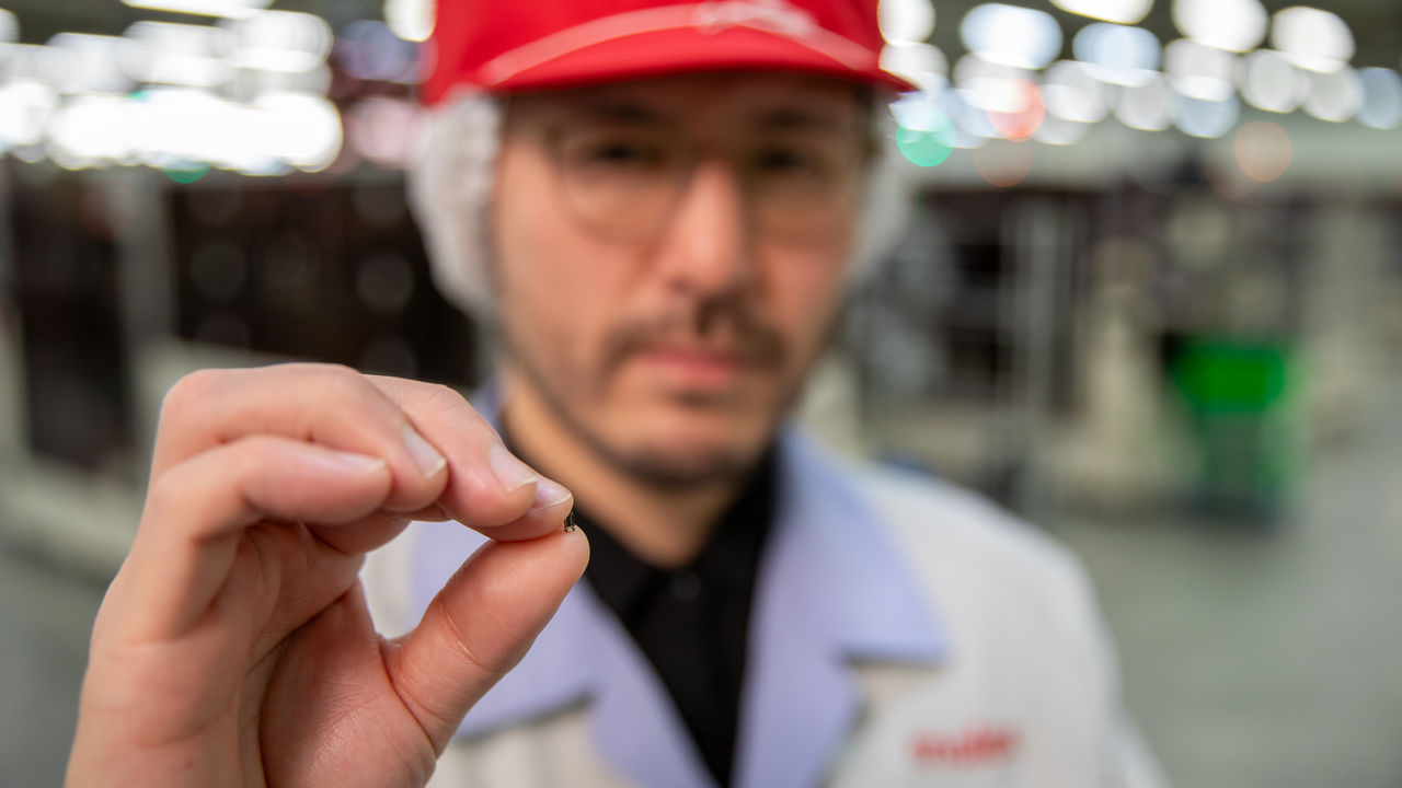 Man holding Molex Quad-Row interconnect to demonstrate it is the size of a grain of rice. 