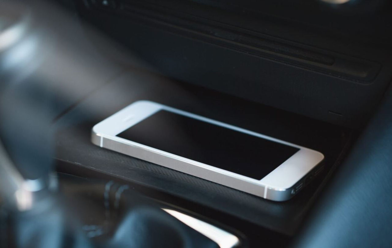 A phone wirelessly charging on a vehicle console.