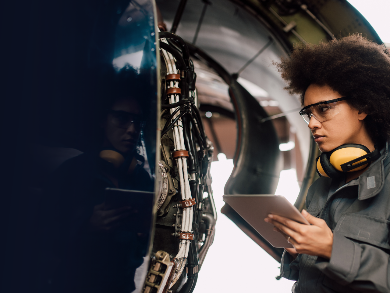 Woman with clipboard inspecting electronic equipment in military vehicle. 